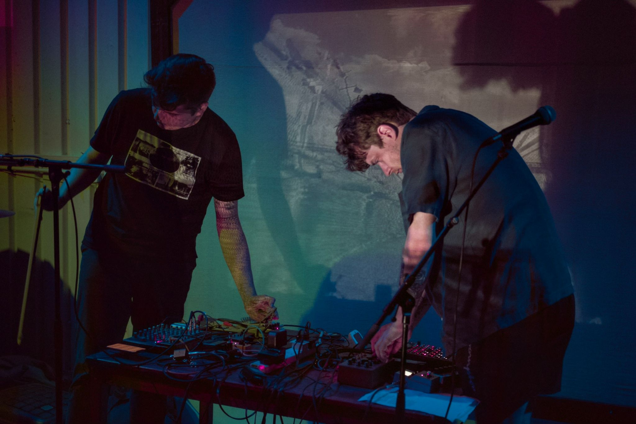 a black and white photograph showing the Degredation duo playing in front of Monty's Thames Estuary visuals